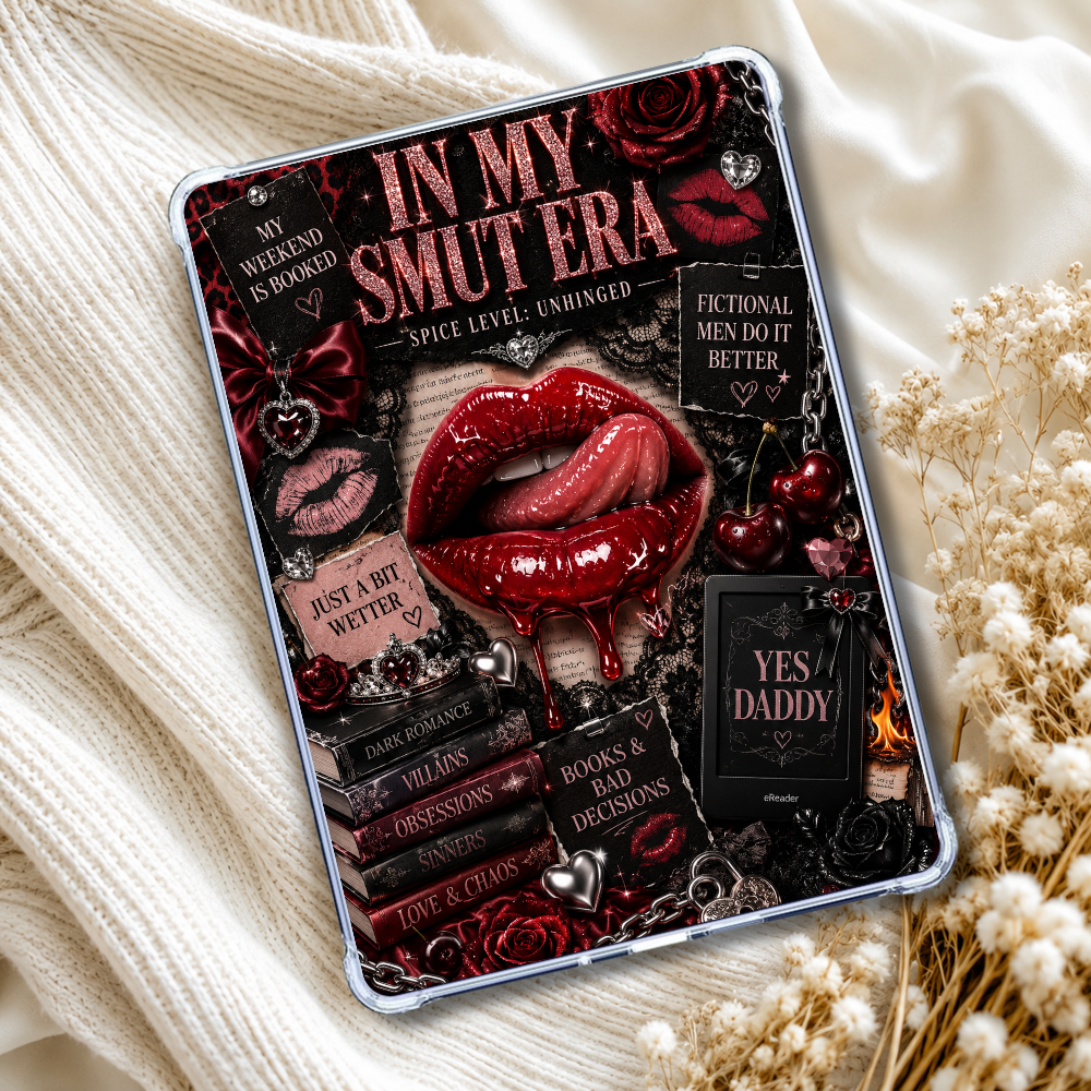 A tablet device displaying a gothic-themed graphic design with red lips, roses, books, and text like 'In My Smut Era' and 'Yes Daddy,' styled on cream fabric with dried flowers.